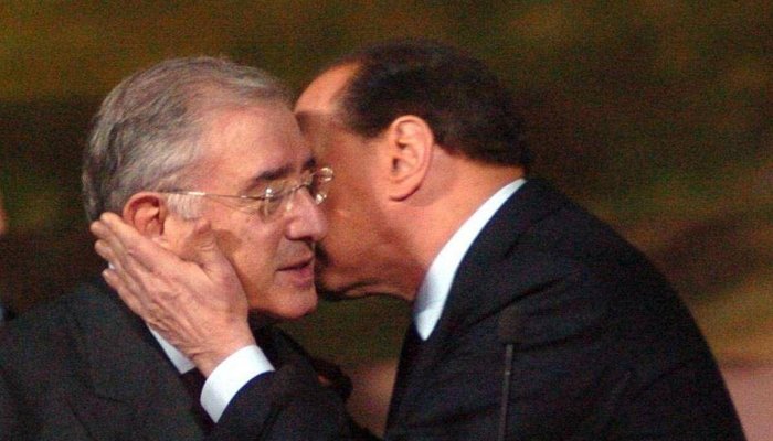Silvio Berlusconi e Marcello Dell'Utri guancia a guancia, con la mano di Berlusconi sul viso di Dell'Utri